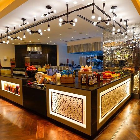 Jabal Omar Hyatt Regency Makkah Hotel Mecca Exterior foto The photo shows a stylish and modern buffet area in a restaurant or hotel. The design features a sleek counter with various food items displayed, including fresh fruits. The space is well-lit with pendant lights hanging from the ceiling, creating a w