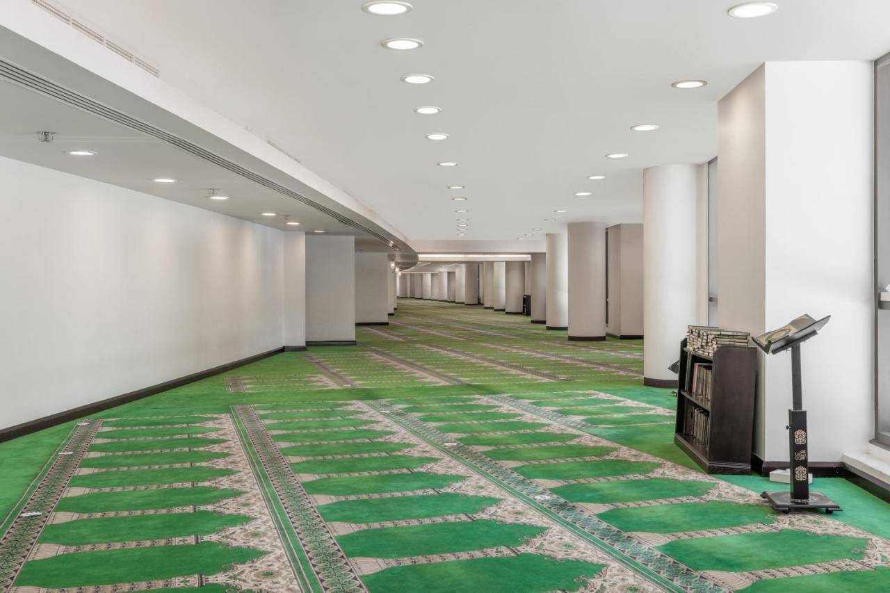 Jabal Omar Hyatt Regency Makkah Hotel Mecca Exterior foto The photo shows a spacious, well-lit indoor area with a green carpet designed for prayer. The carpet features a decorative pattern and outlines spaces where individuals would pray. There are white walls and several light fixtures in the ceiling provi