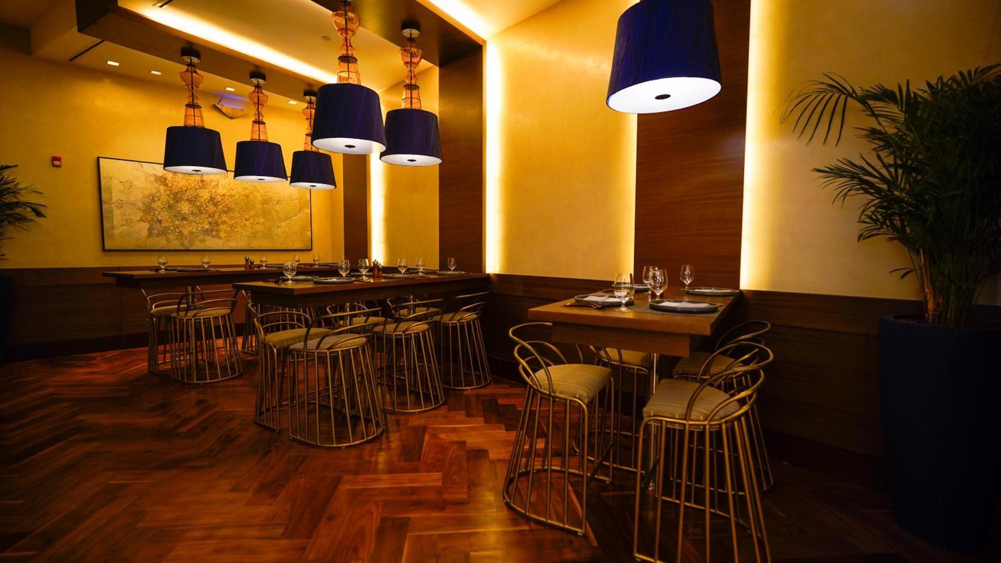 Jabal Omar Hyatt Regency Makkah Hotel Mecca Exterior foto The photo shows an elegantly designed restaurant interior. It features stylish seating arrangements with gold wire chairs paired with tables. The ambient lighting is warm, with a mix of recessed lights and pendant lamps that have blue shades, creatin