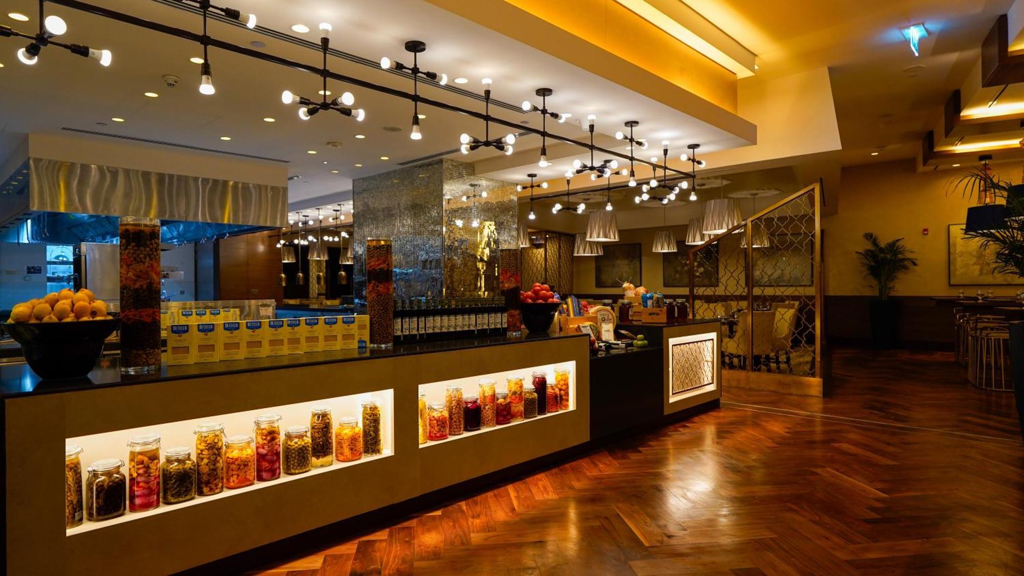 Jabal Omar Hyatt Regency Makkah Hotel Mecca Exterior foto The photo shows a stylish interior of a restaurant or café. It features a well-lit space with modern lighting fixtures hanging from the ceiling. The focal point is a counter area with jars filled with colorful ingredients or snacks, illuminated by li