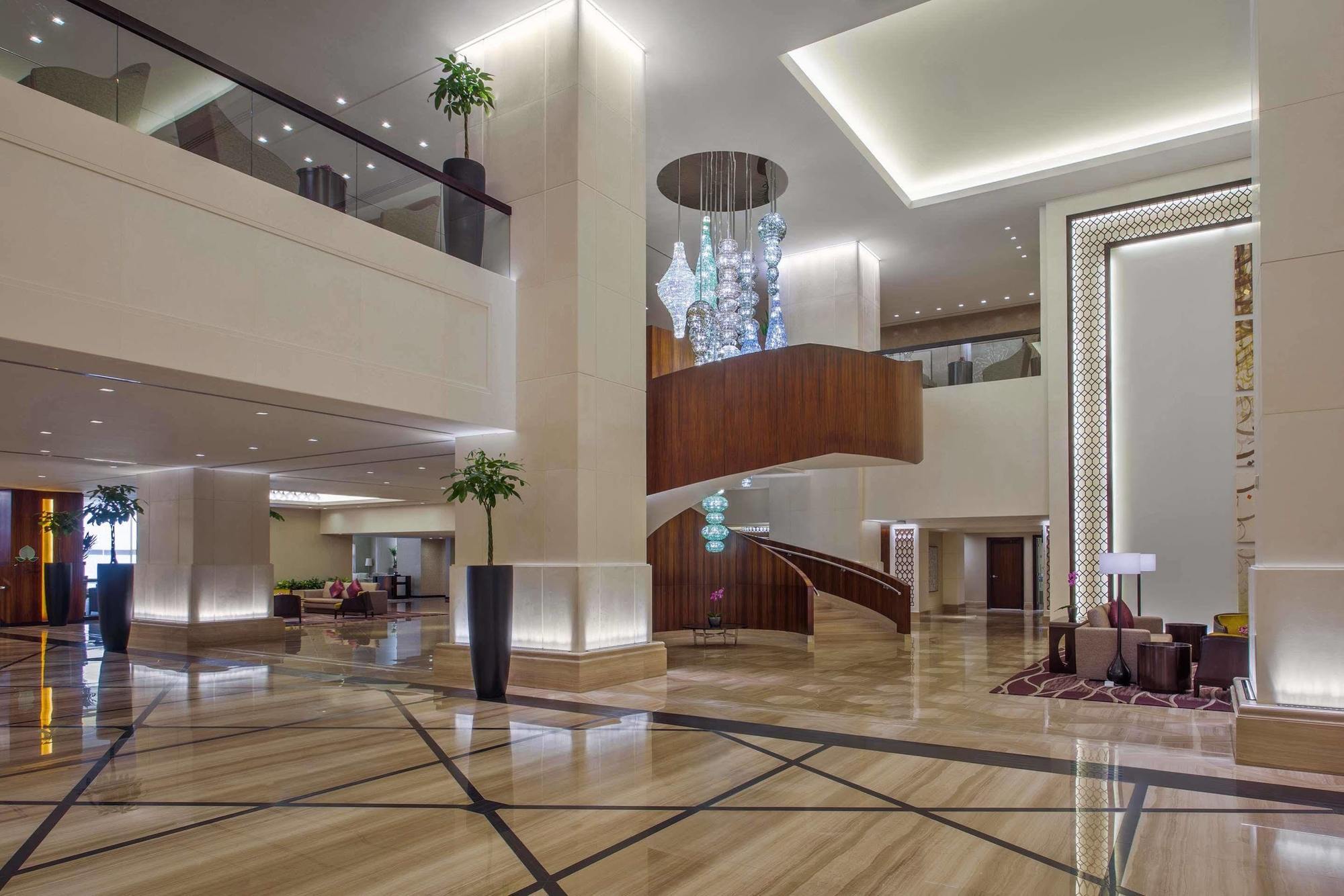Jabal Omar Hyatt Regency Makkah Hotel Mecca Exterior foto The photo shows a spacious and elegantly designed hotel lobby. The interior features large marble flooring with a geometric pattern, complemented by modern lighting fixtures. A grand staircase with wooden accents is prominent in the center, leading t