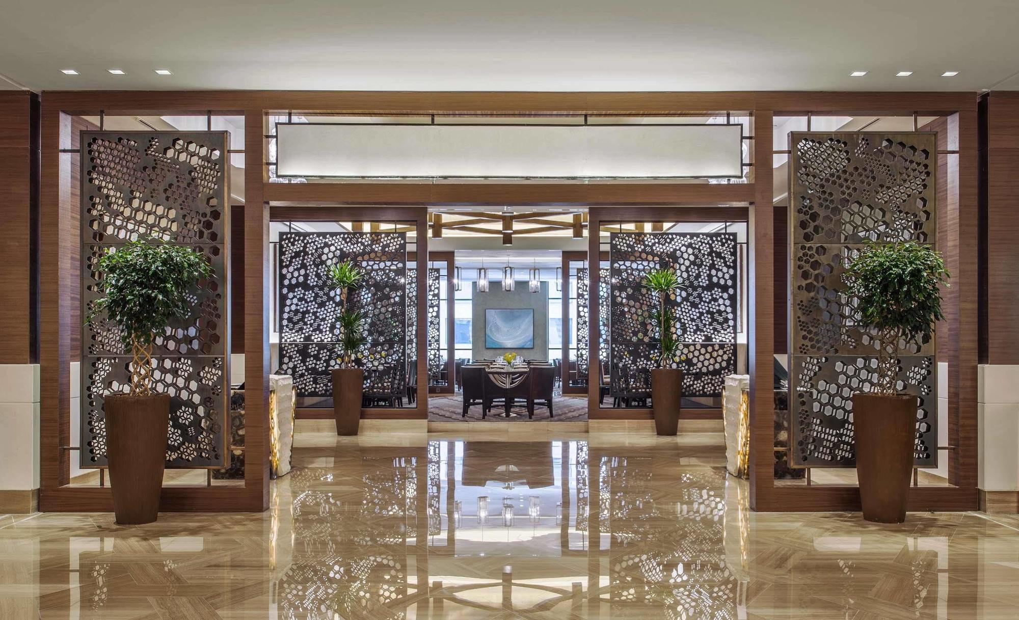 Jabal Omar Hyatt Regency Makkah Hotel Mecca Exterior foto The image shows an elegant interior space, likely the lobby or entrance of a luxurious hotel or restaurant. The area features decorative partitions with intricate designs, framed by wooden structures. These partitions create a sense of separation whi