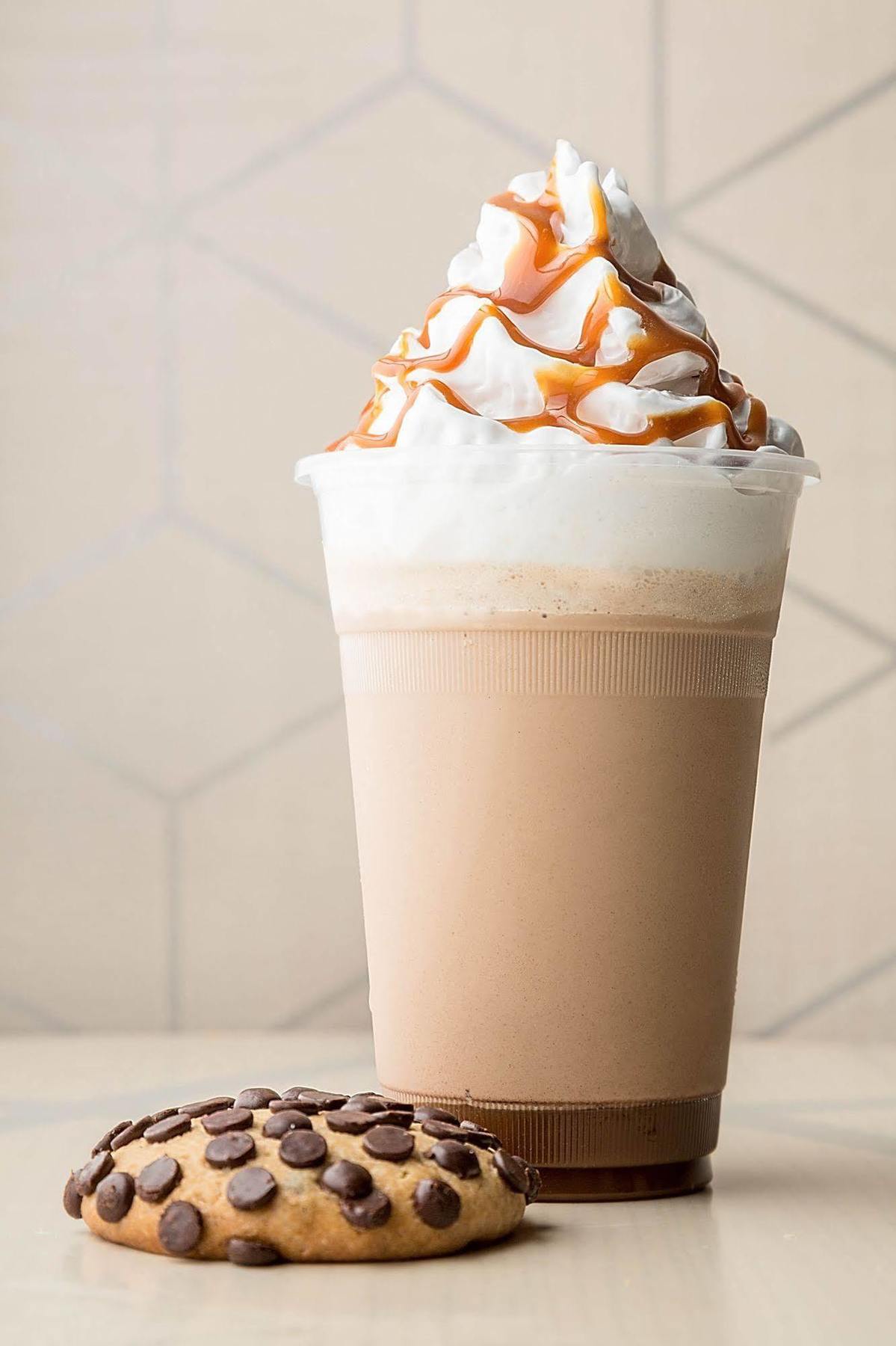 Jabal Omar Hyatt Regency Makkah Hotel Mecca Exterior foto The photo shows a tall cup of a creamy beverage, likely a milkshake or a blended coffee drink. The drink has a light brown color with a frothy top, which is topped with whipped cream. Drizzled over the whipped cream is a thick caramel sauce, adding a