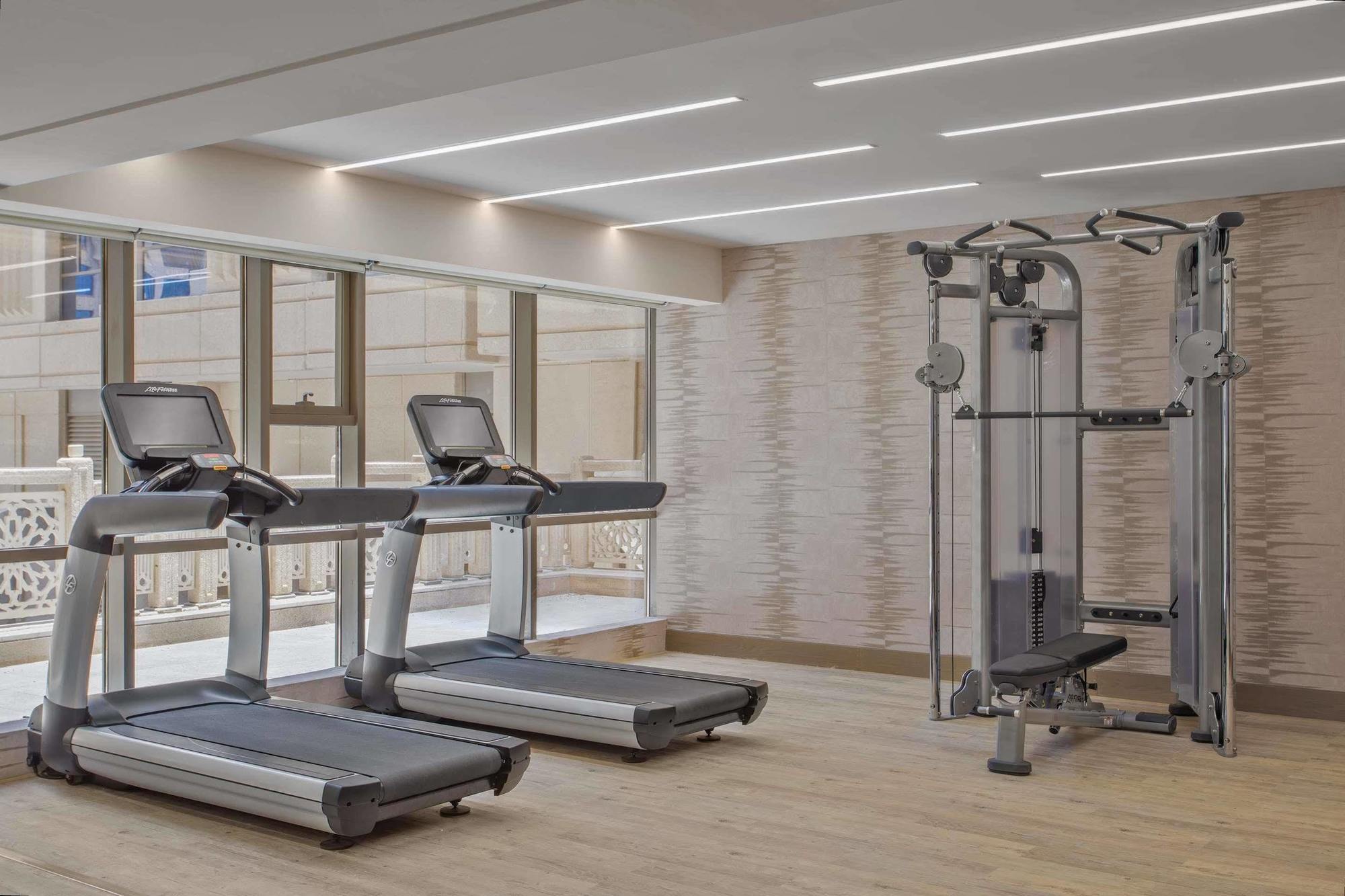 Jabal Omar Hyatt Regency Makkah Hotel Mecca Exterior foto The photo shows a modern gym area featuring two treadmills positioned side by side. Next to them is a multi-functional gym machine designed for strength training, which includes various attachments for different exercises. The gym has a bright, airy 