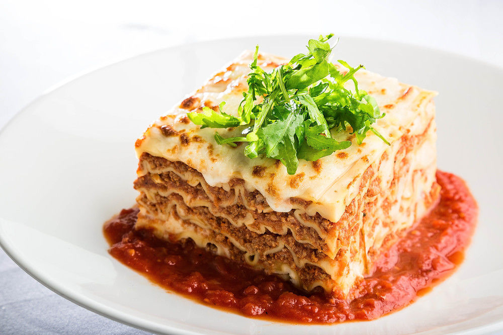 Jabal Omar Hyatt Regency Makkah Hotel Mecca Exterior foto The photo shows a serving of lasagna, which is a layered pasta dish. The lasagna has multiple layers, with a combination of meat, cheese, and béchamel sauce, topped with a sprinkle of fresh green herbs. It sits on a plate with a rich red tomato sauce