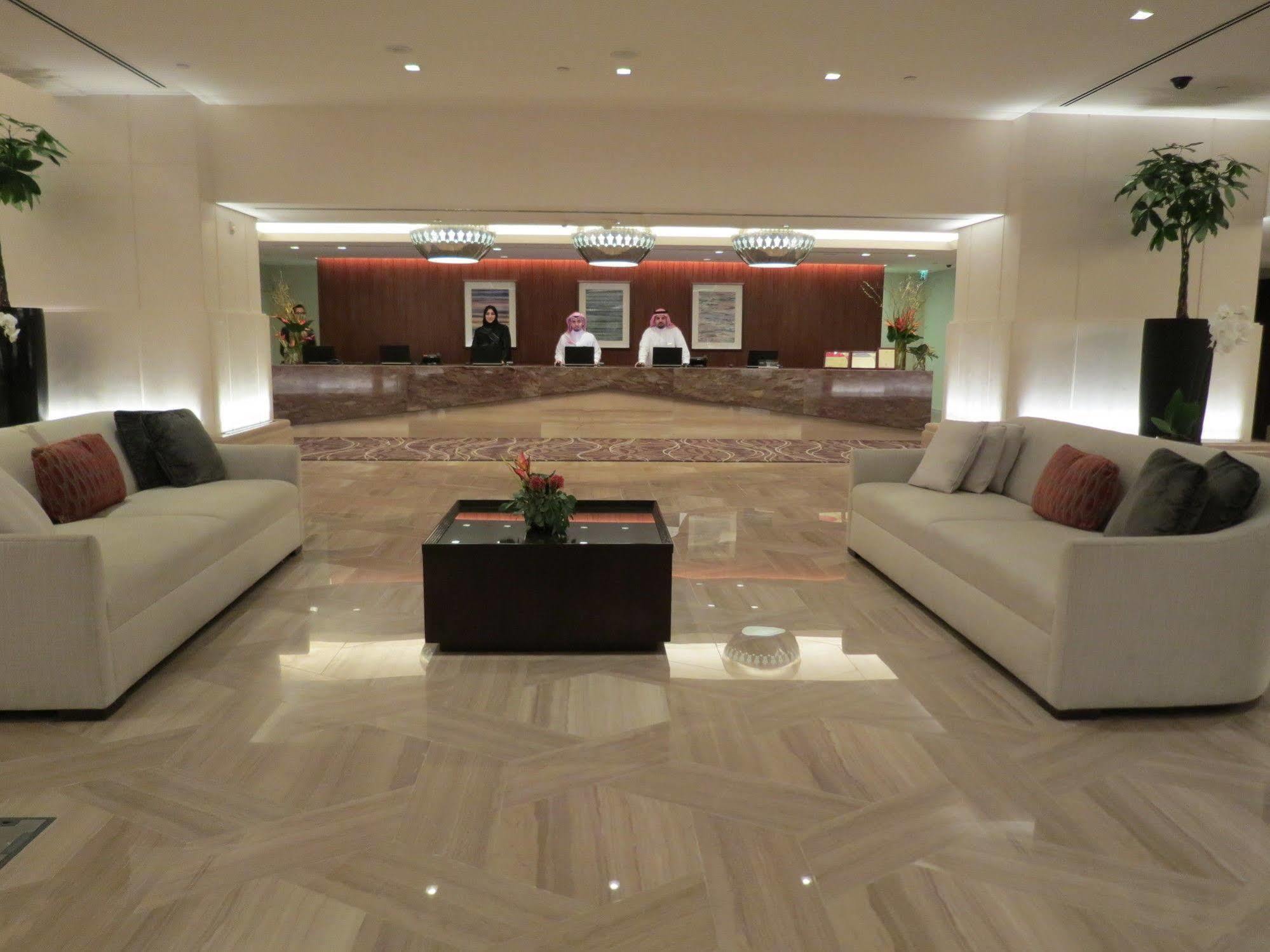Jabal Omar Hyatt Regency Makkah Hotel Mecca Exterior foto The photo shows a modern hotel lobby. In the foreground, there are two light-colored sofas with decorative pillows, positioned facing each other. A small coffee table with a plant sits between the sofas. 

In the background, there is a reception desk