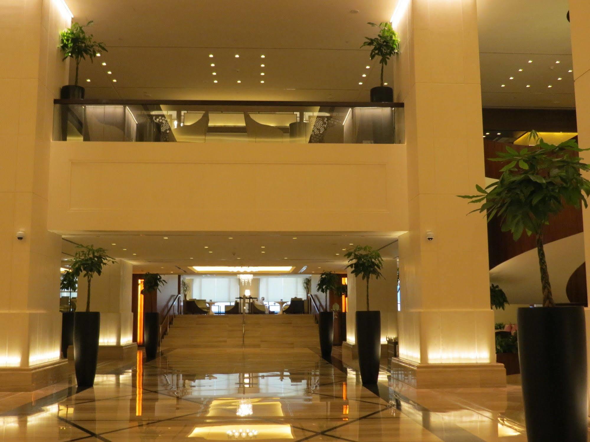 Jabal Omar Hyatt Regency Makkah Hotel Mecca Exterior foto The photo shows a spacious and elegantly designed hotel lobby. It features a multi-level layout with a set of stairs in the center leading to an upper floor. The lobby is well-lit with a warm glow from recessed lighting, and there are decorative plan